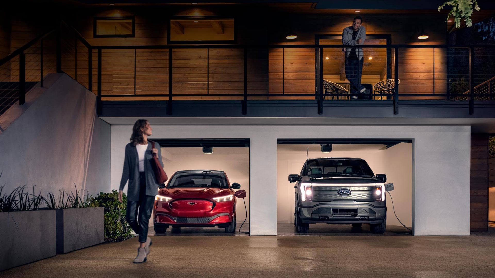 Woman walking out from home garage with a 2024 Mustang® Mach-E and Ford Lightning® truck in plugged-in and charging | Freeport Ford in Freeport IL